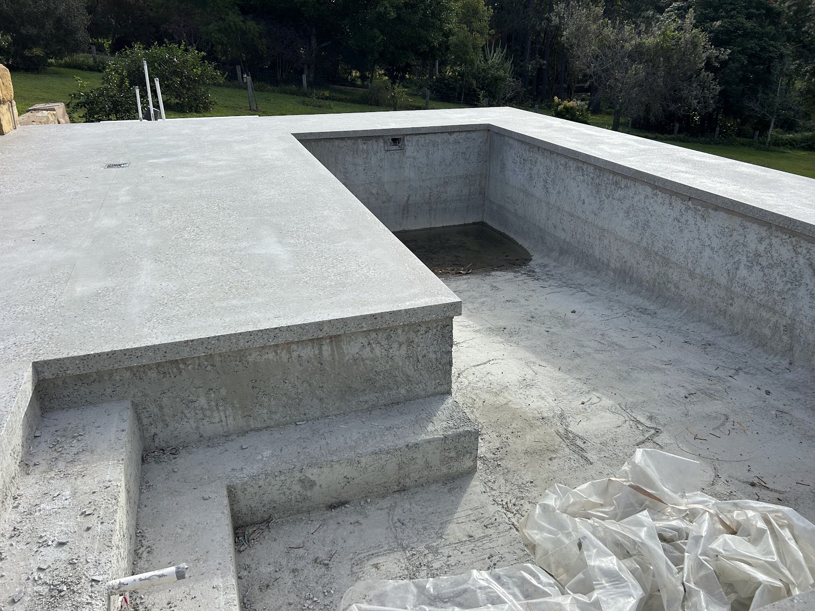 Freshly poured concrete pool shell with a built-in step and swim-out ledge