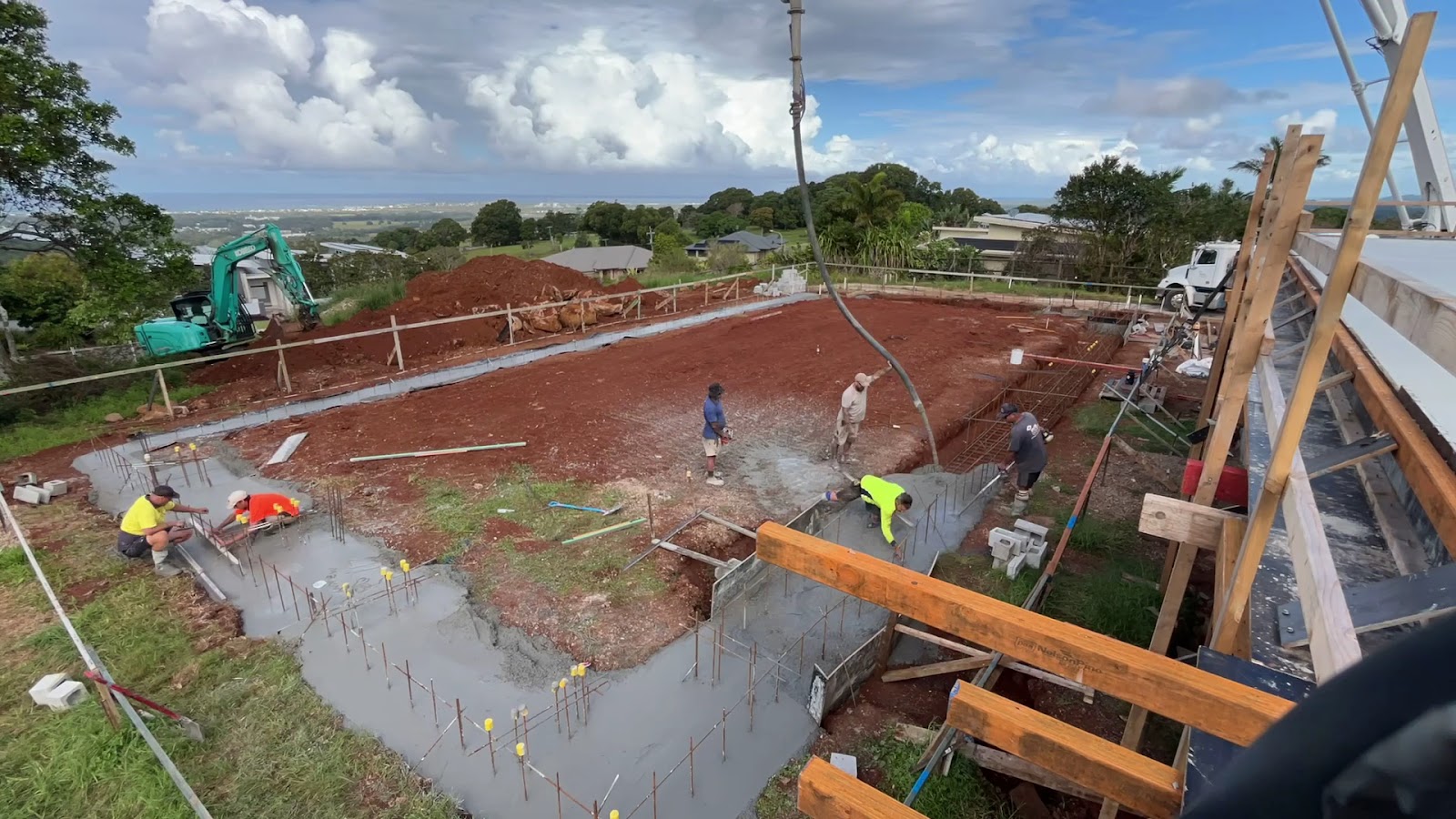 Crew pouring and screeding a pool floor on a hillside site with views to the coast
