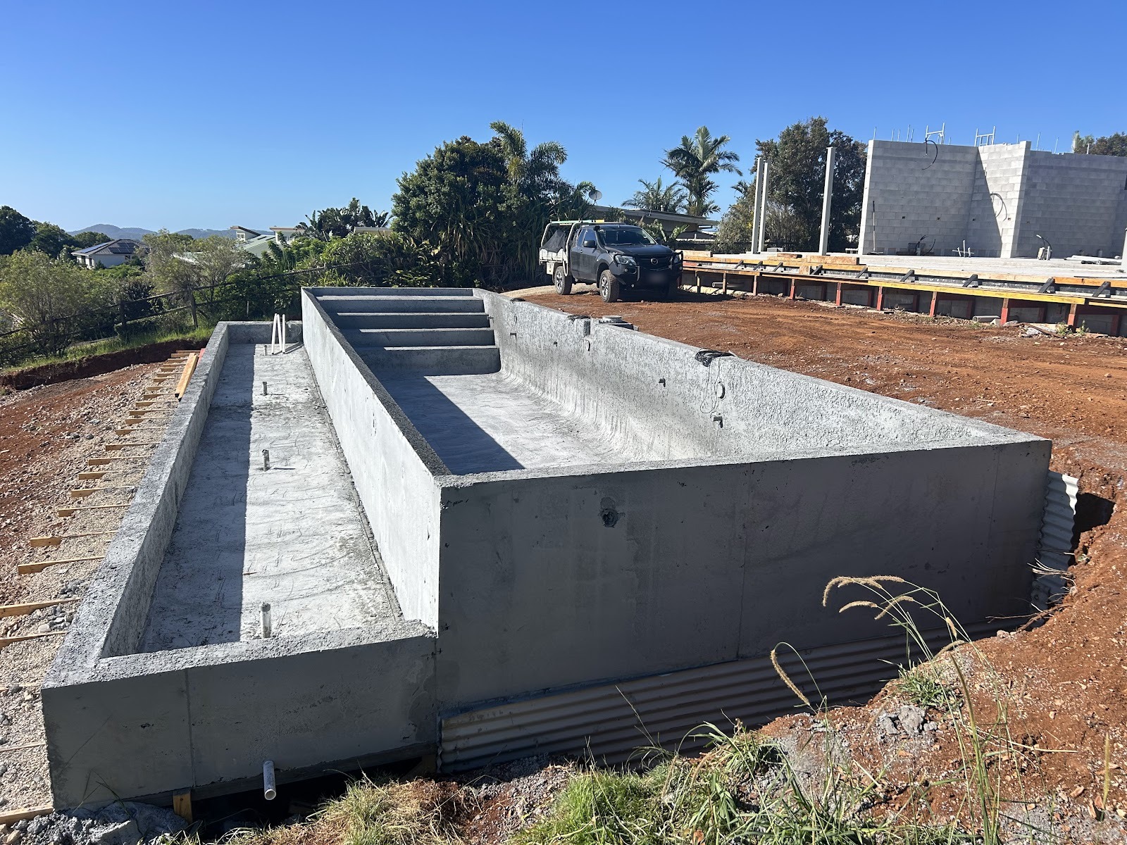 A finished concrete pool shell with a built-in step ledge on a hilltop block