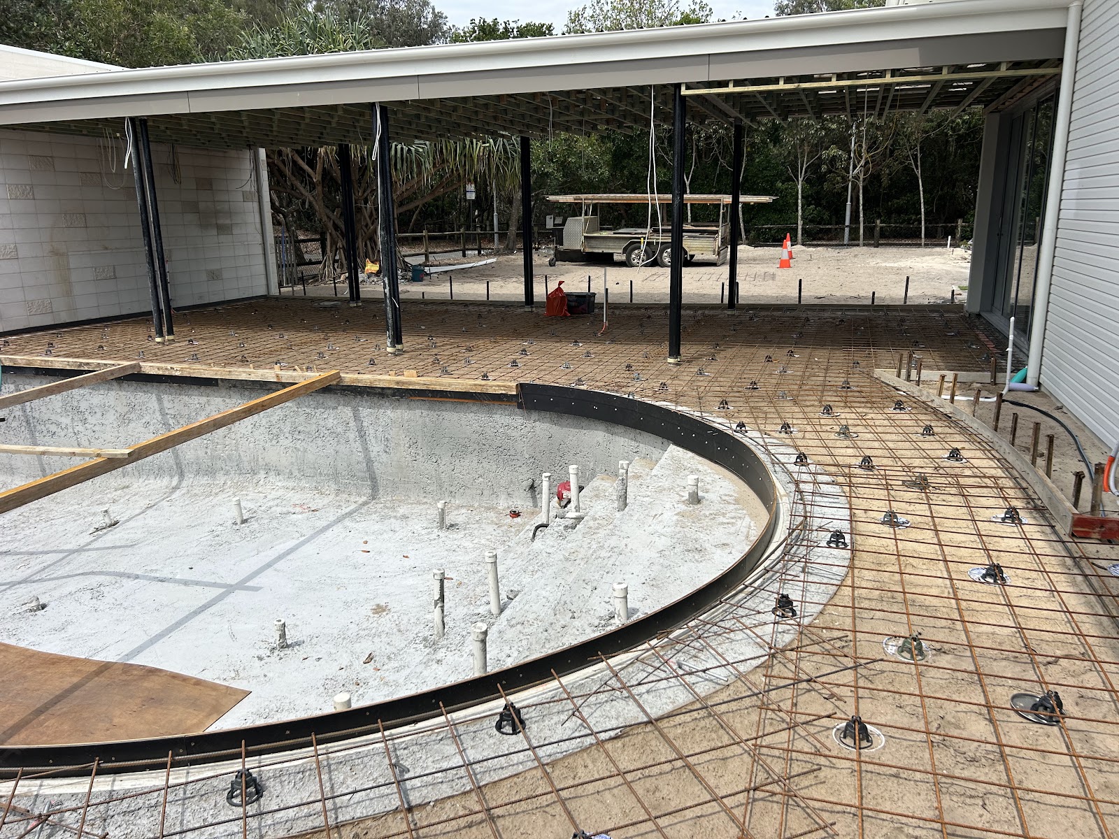 Curved pool shell with its reinforced surround set out under a new pavilion